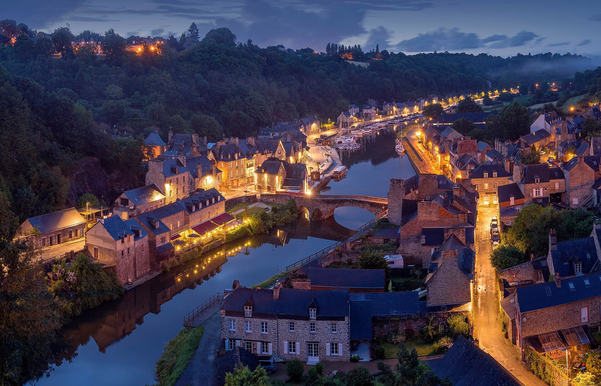 A river town at dusk, its houses, quay and streets lit